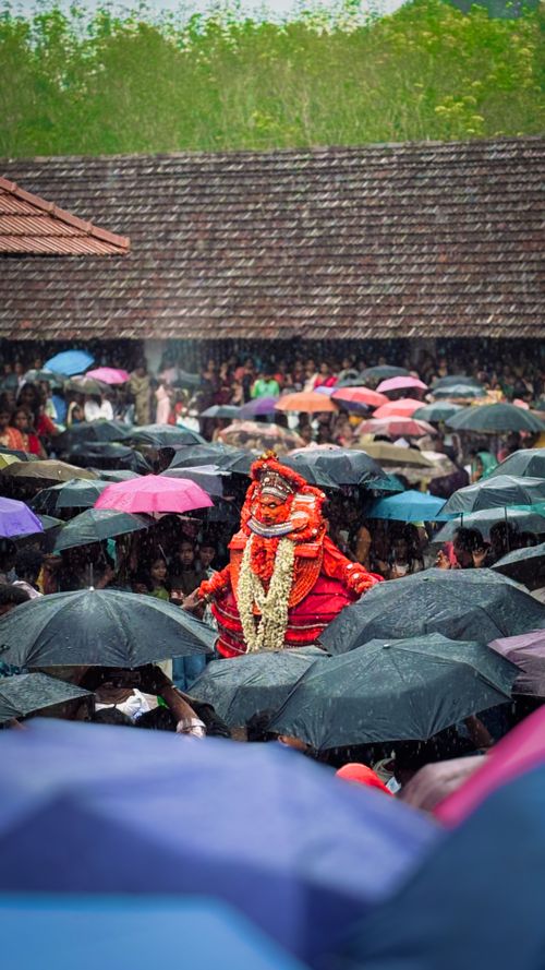 Free A vibrant parade in the rain with a performer in traditional attire surrounded by colorful umbrellas. Stock Photo