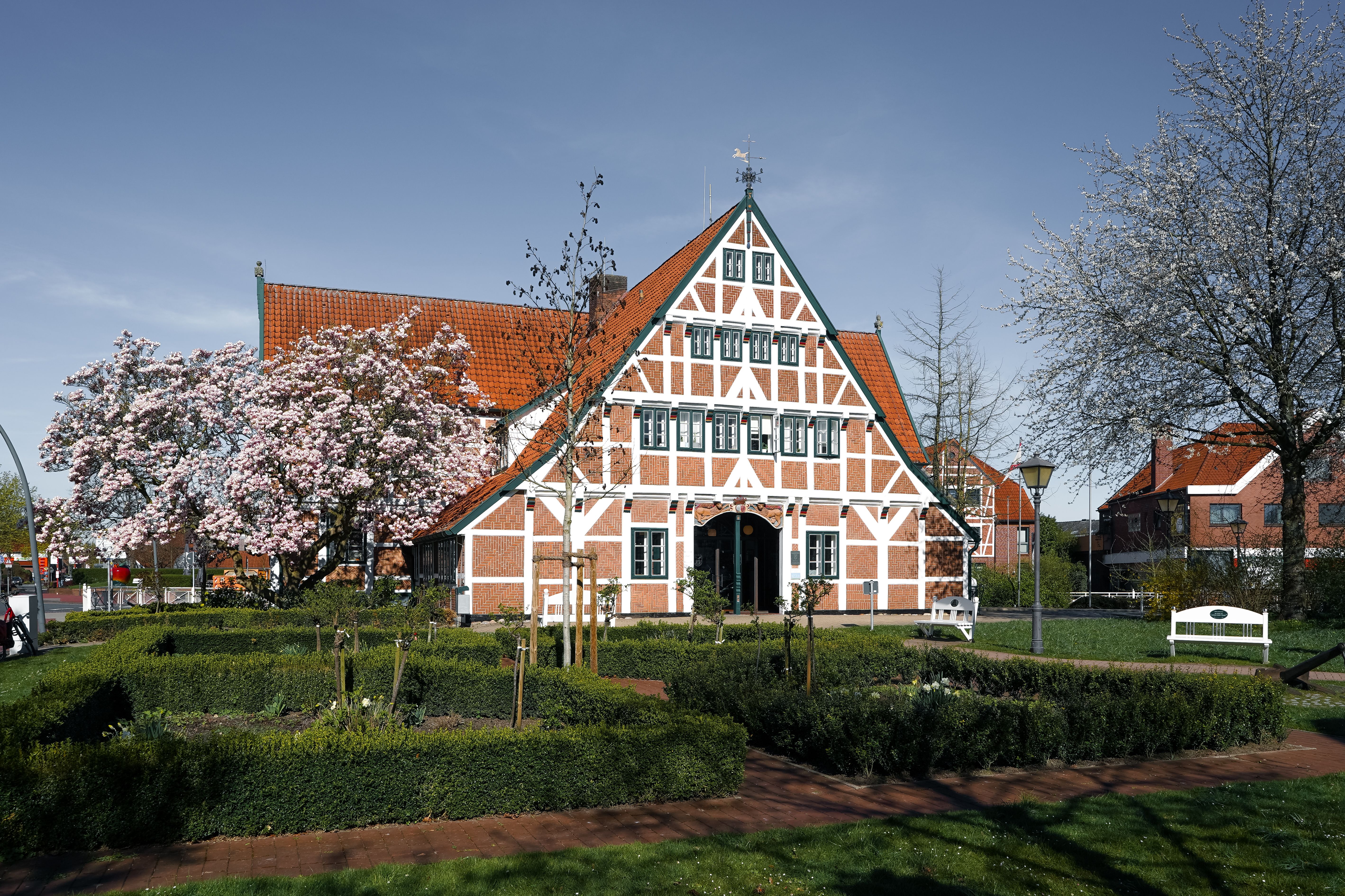 Picturesque half-timbered house with blooming trees in Jork, Niedersachsen.