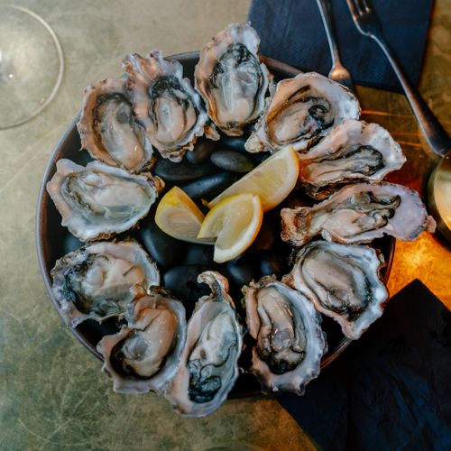 Free A top view of fresh oysters on a platter with lemon wedges, ready to serve. Stock Photo