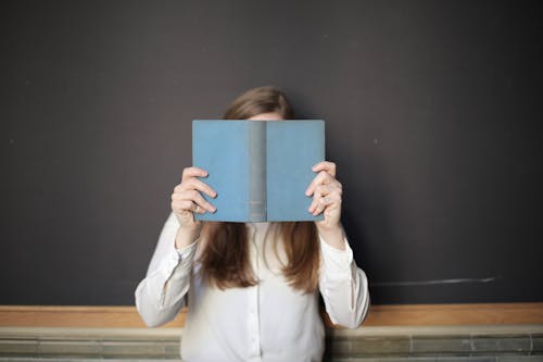 Mujer En Camisa Blanca De Manga Larga Con Libro Azul