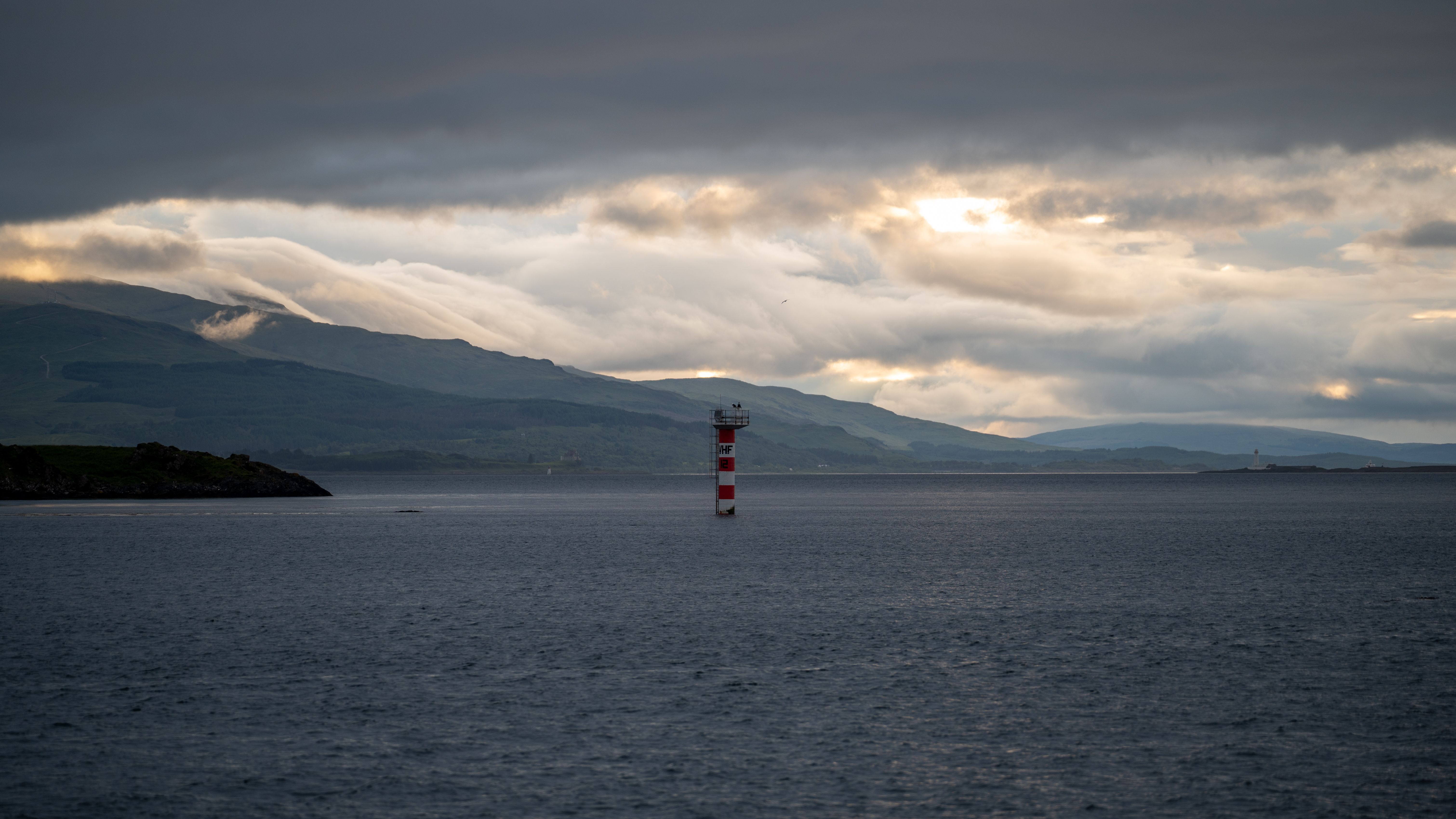 Dramatic sky over the sea with a lighthouse near Oban, Scotland.
