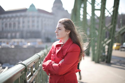 Woman in Red Coat Standing Near Metal Railing