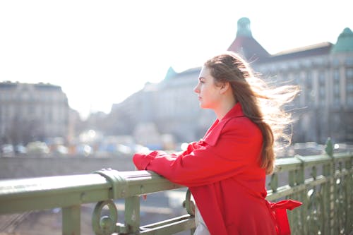 Woman in Red Coat Standing Near Metal Railing