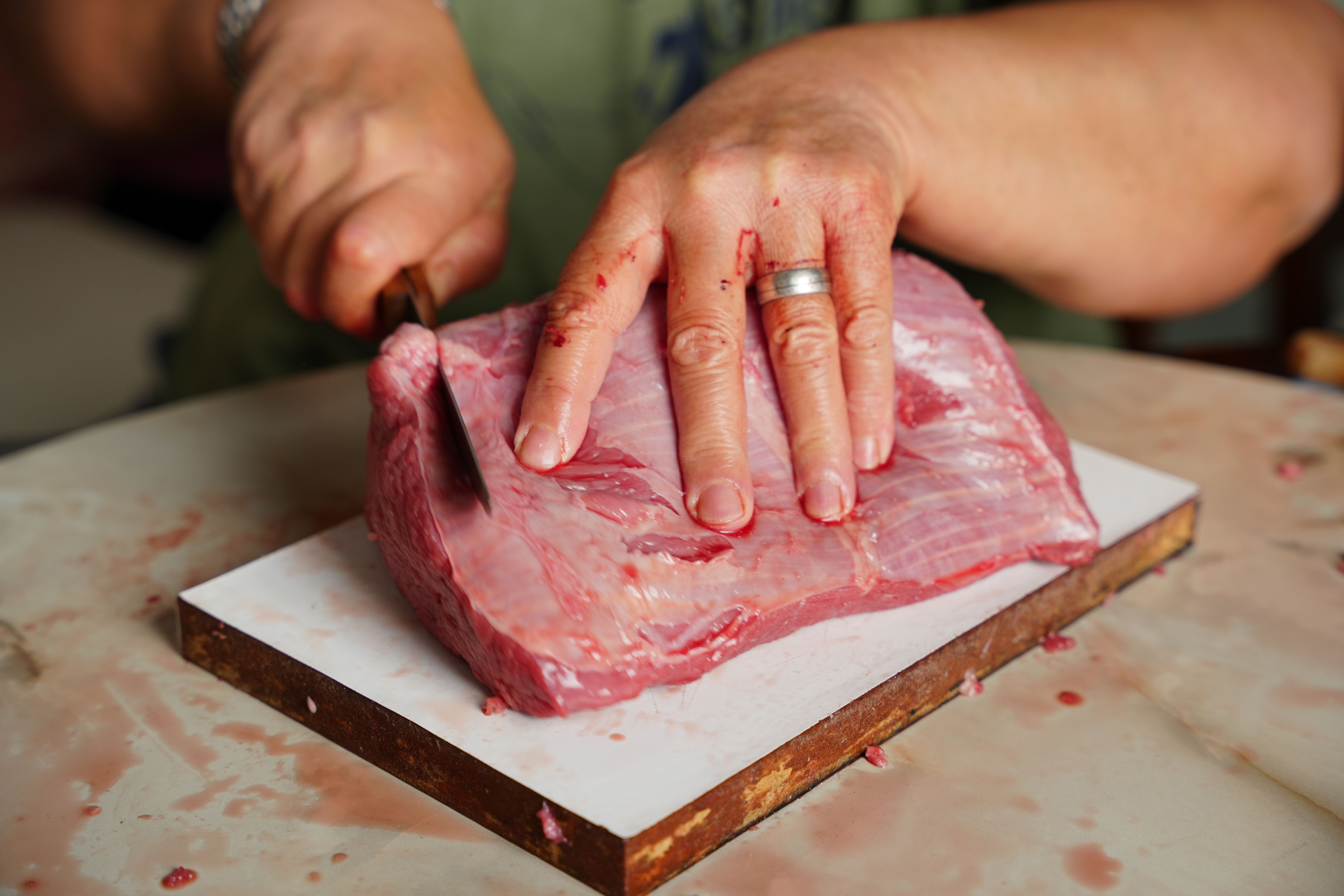 Butcher slicing a thick halal sirloin steak at a North London butcher shop counter