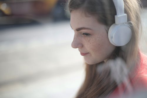 Wanita Mendengarkan Musik Menggunakan Headphone Putih