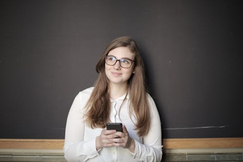 Woman in White Long Sleeve Shirt Holding Black Smartphone