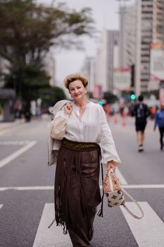 Stylish woman in urban setting, wearing bohemian outfit, confidently crossing a city street.