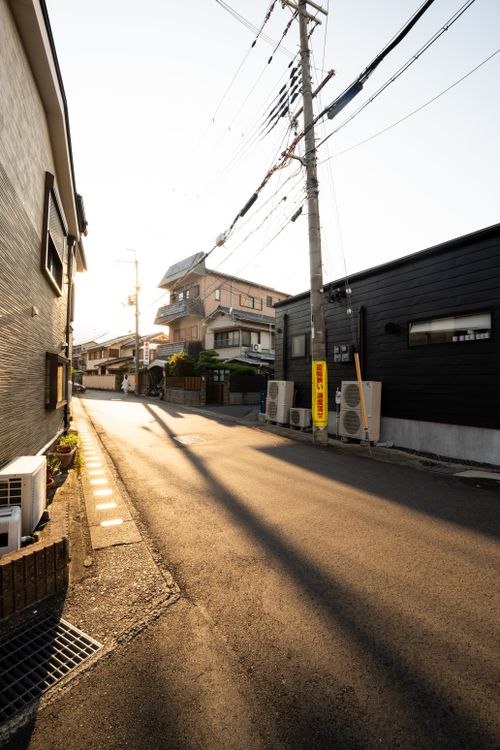 Free A serene street view in Kyoto, Japan with sunlight casting long shadows. Peaceful urban scene. Stock Photo
