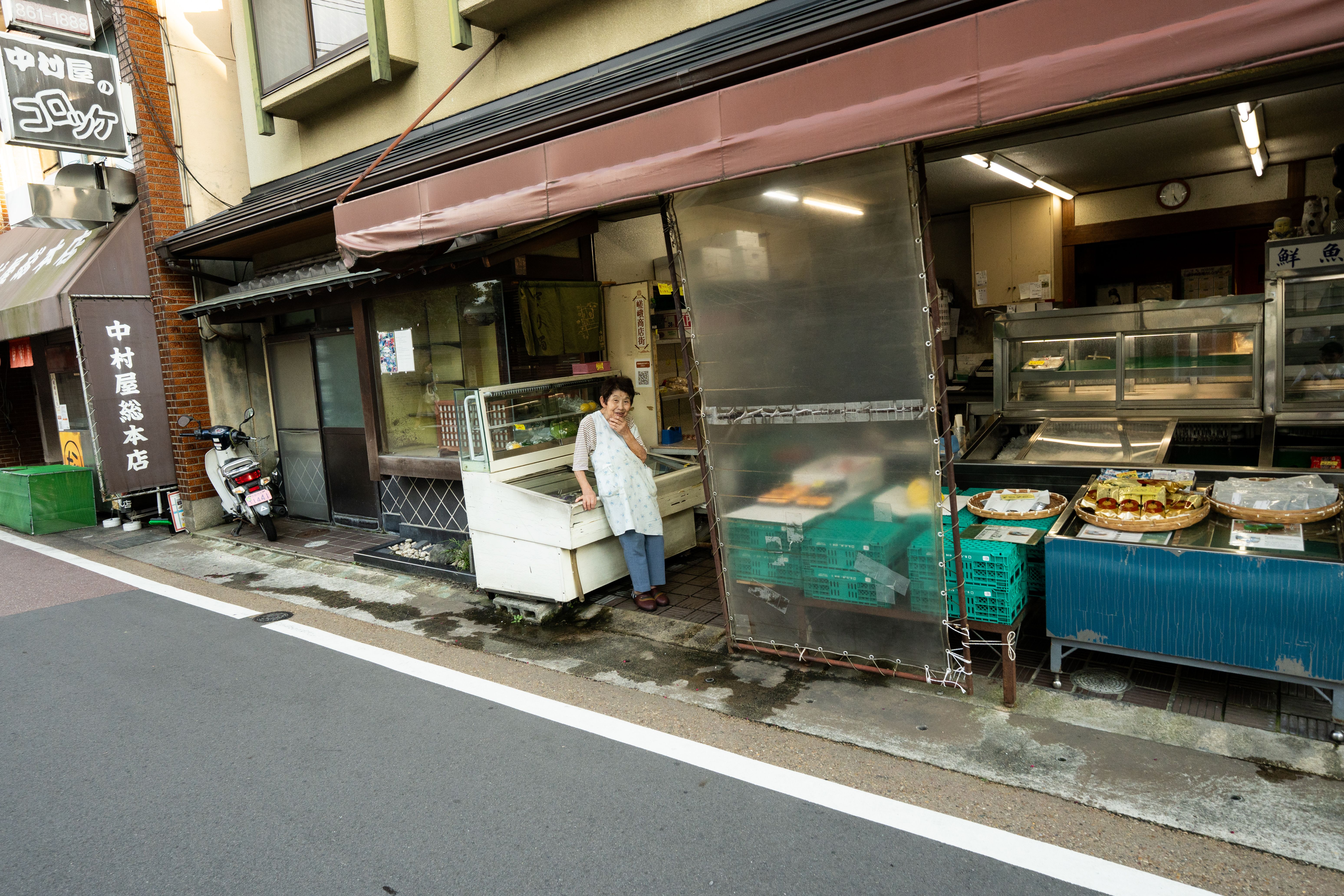 Charming traditional street shop in Kyoto with local goods and an owner standing outside.