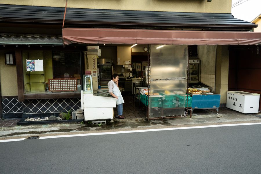 A traditional Kyoto shop with a local vendor standing at the entrance, showcasing Japanese culture.