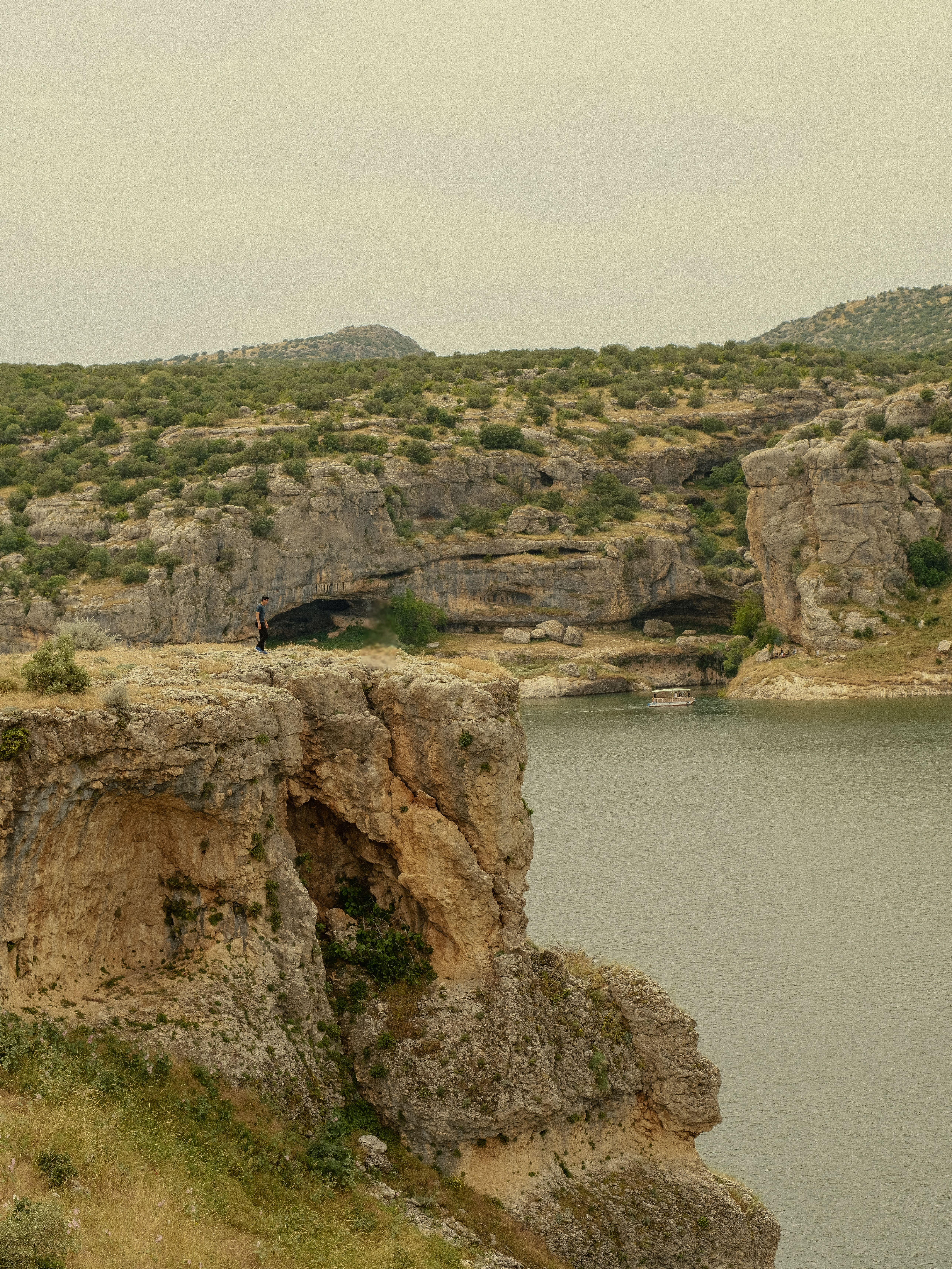 Serene view of rocky cliffs and a calm river in Şanlıurfa, Türkiye, offering natural beauty and tranquility.