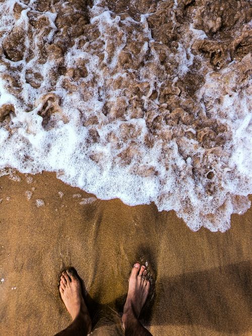Free Feet standing on sandy Casablanca beach with ocean waves. Perfect for travel and lifestyle themes. Stock Photo