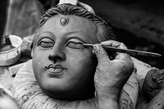 A skilled artisan shapes a clay idol with meticulous detail, highlighting traditional craftsmanship.