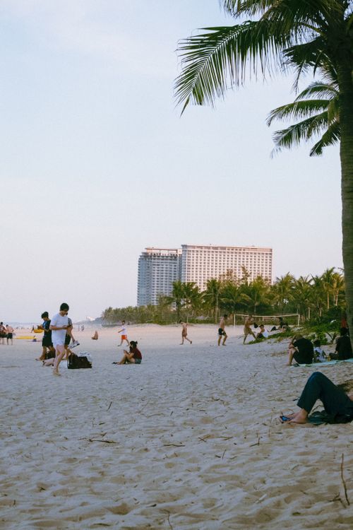 Free A serene beach scene with people enjoying the day near a modern resort hotel. Stock Photo