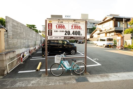 A bicycle parked in an empty parking lot in Kyoto, Japan, with traditional architecture in the background.