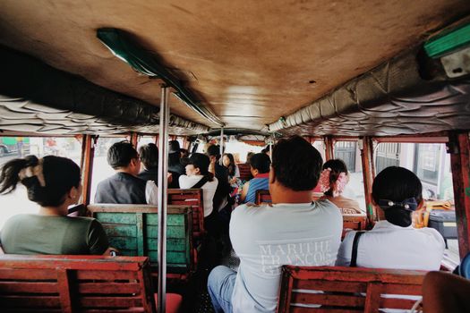 Inside view of a lively jeepney ride with diverse passengers in a bustling city.