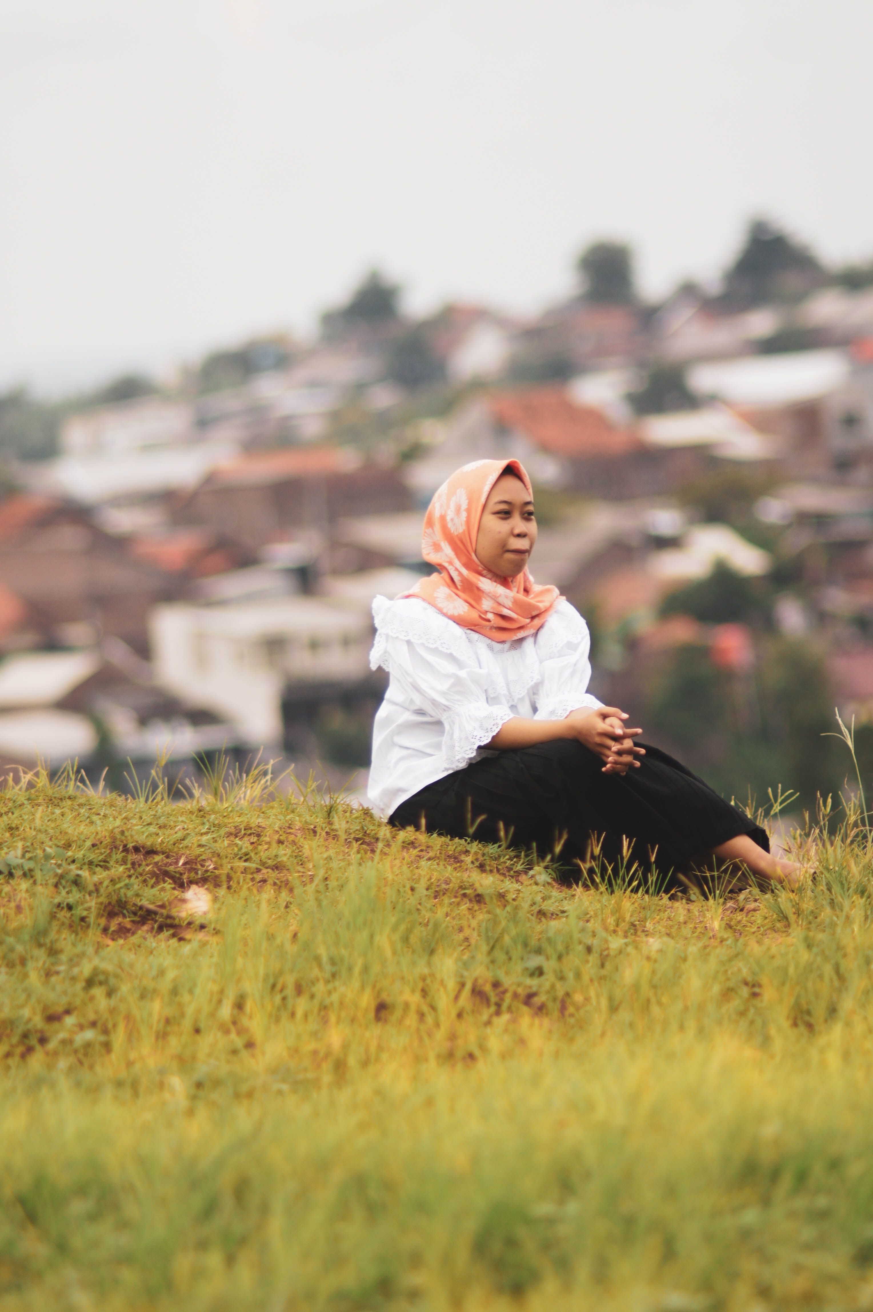 Woman in Orange Hijab Sitting on Grass Field · Free Stock Photo