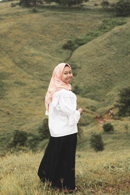 Woman in White Long Sleeve Shirt and Black Skirt Standing on Grass Field