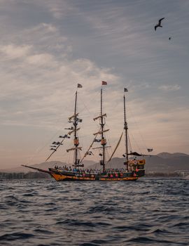 Captivating view of a pirate ship off Cabo San Lucas at sunset, with birds in flight.