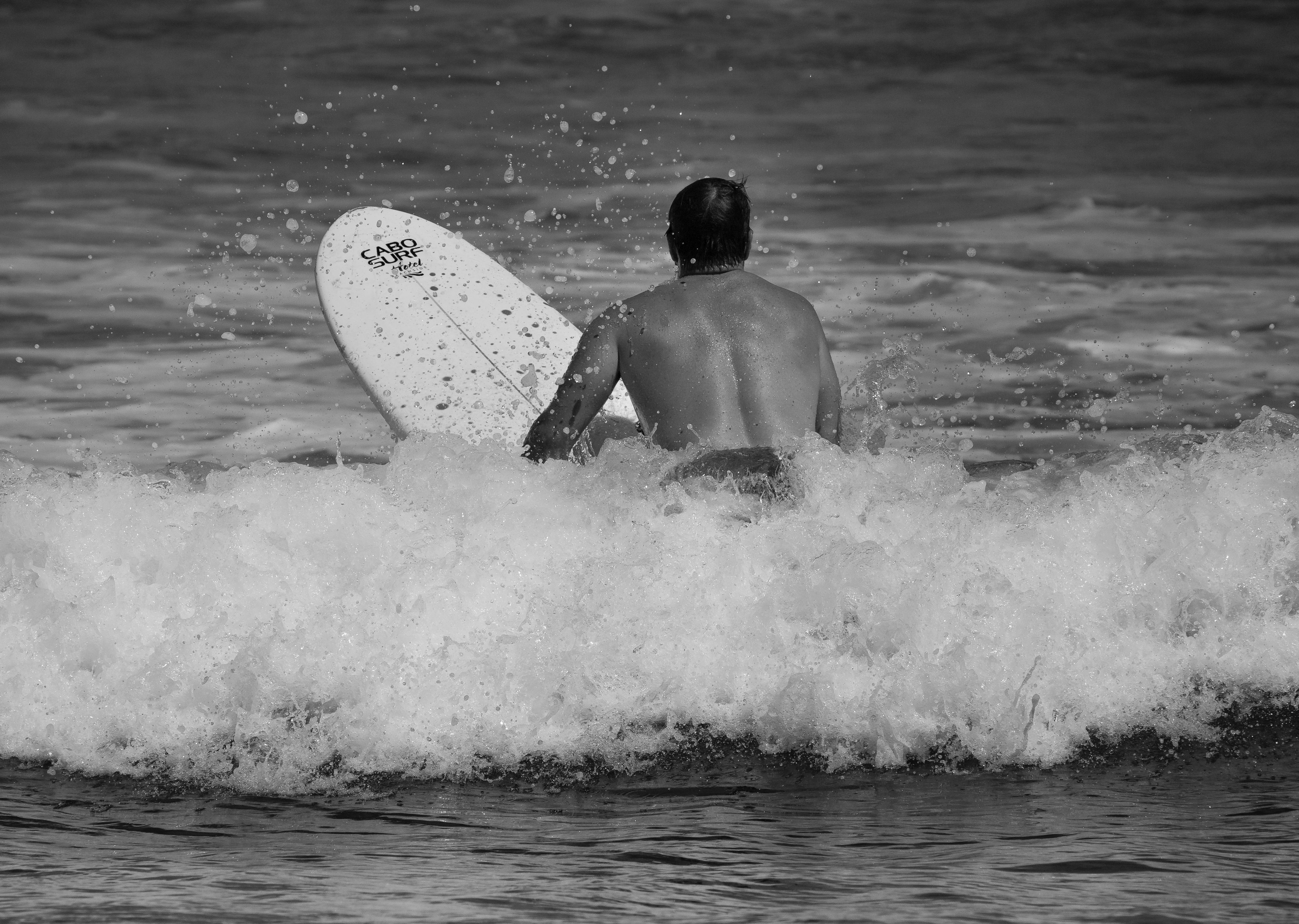 Black and white photo of a surfer riding waves in Cabo San Lucas, Mexico.