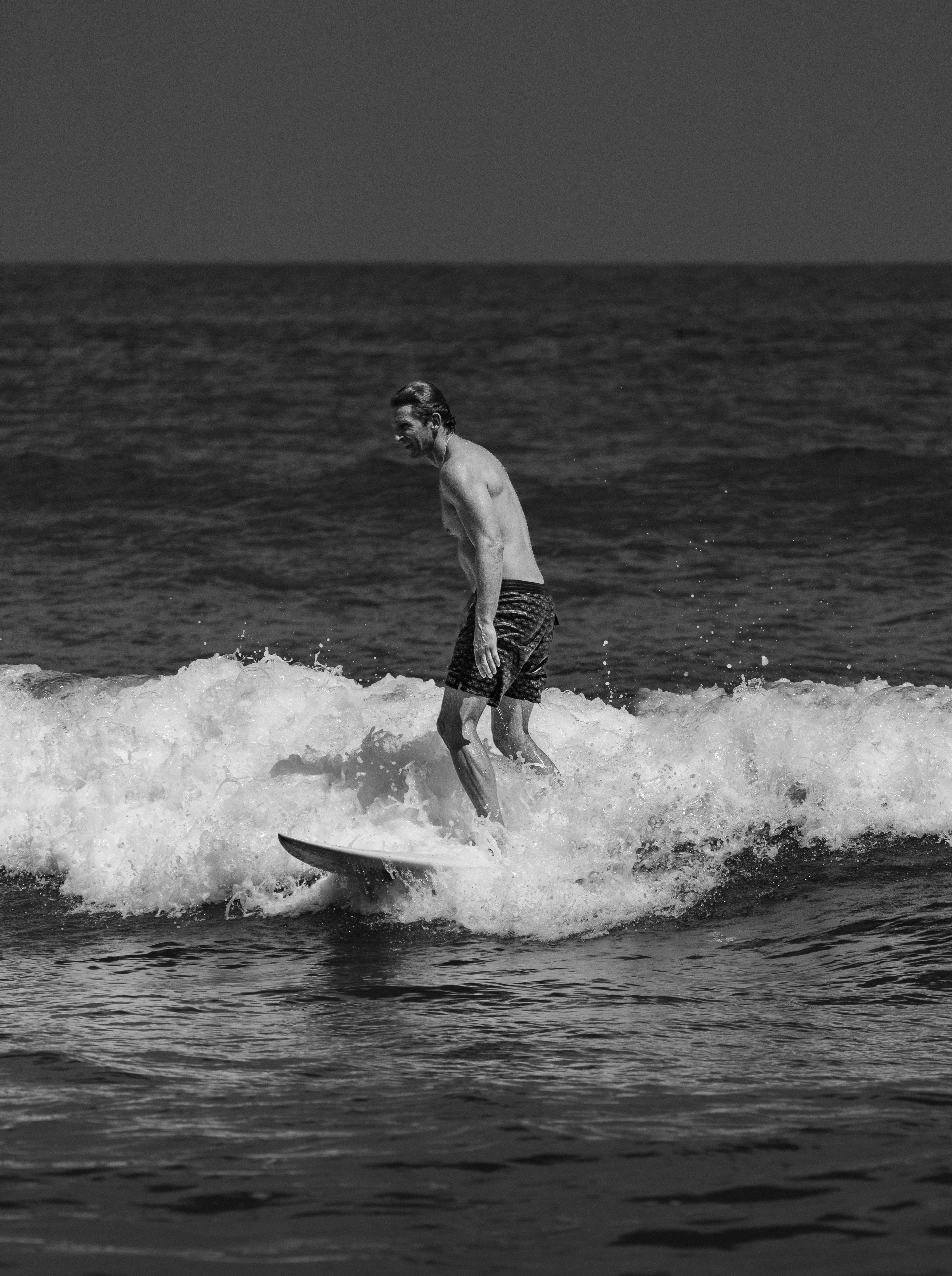 Black and white photo of a surfer enjoying the ocean waves in Cabo San Lucas, Mexico.