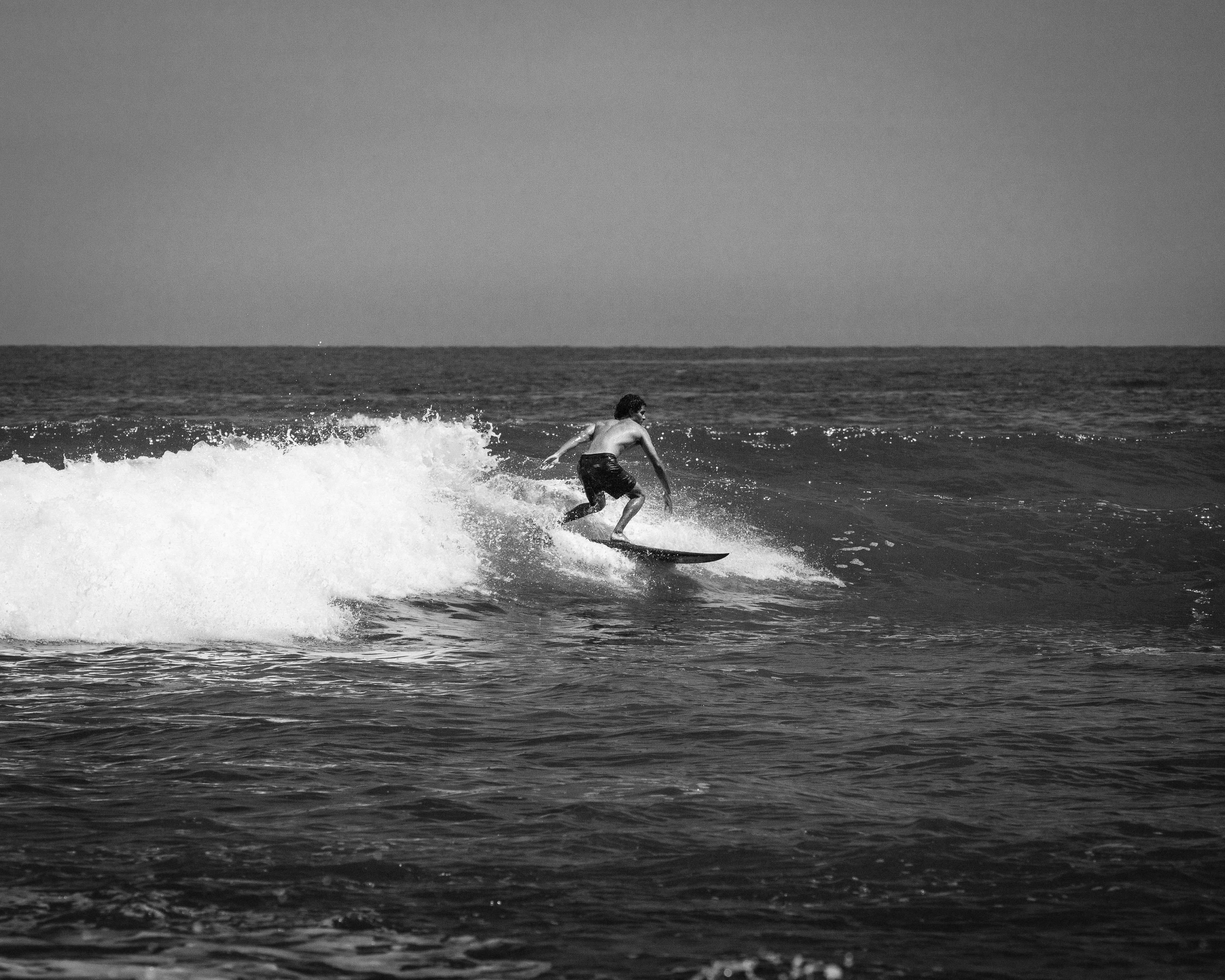Black and white image of a surfer riding waves in Cabo San Lucas, Mexico.
