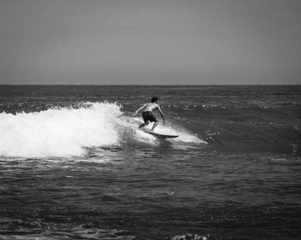 Black and white image of a surfer riding waves in Cabo San Lucas, Mexico.