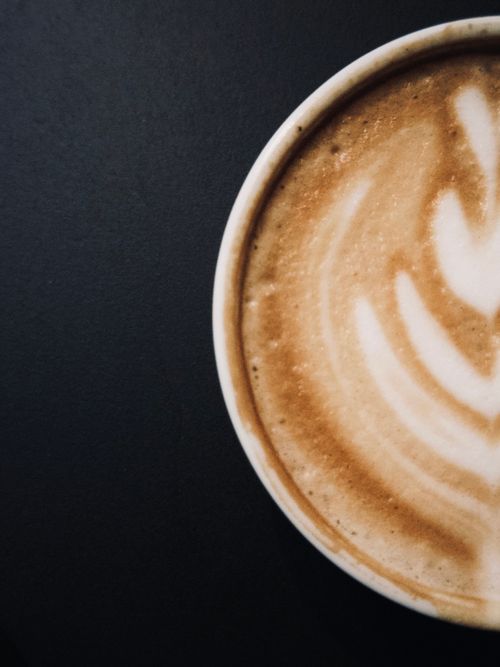 Free Aerial view of a latte with creamy latte art on a dark table. Stock Photo