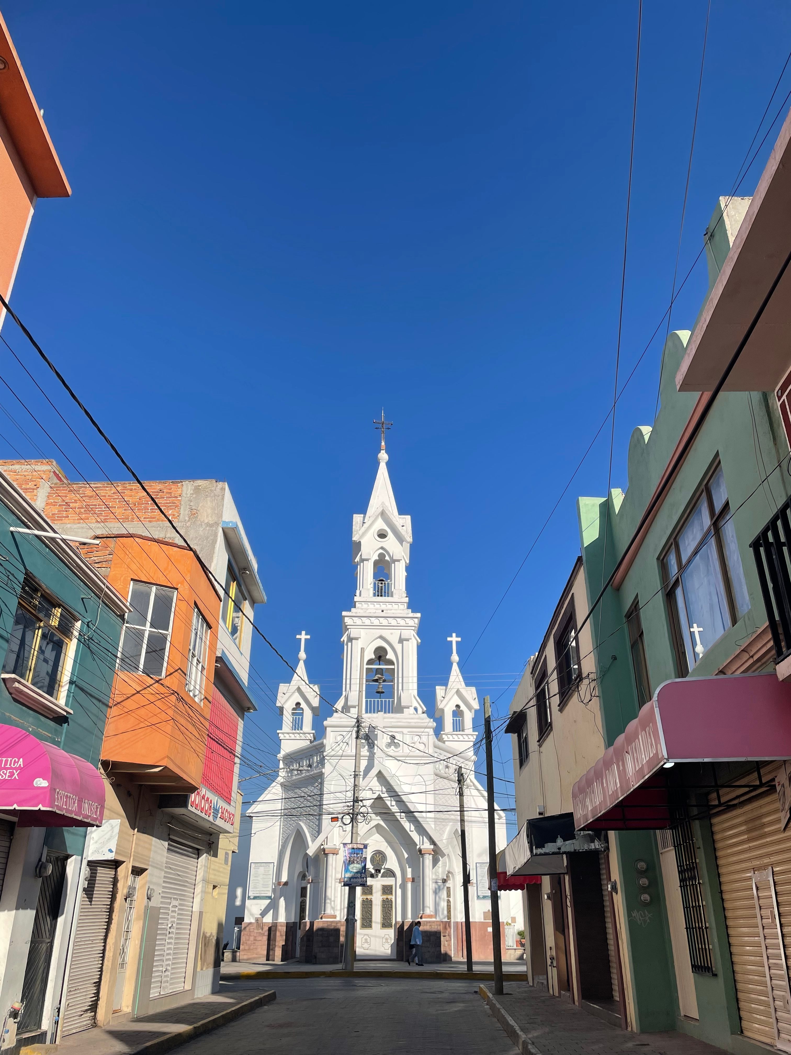 Beautiful church with ornate architecture amidst vibrant buildings on a sunny day.