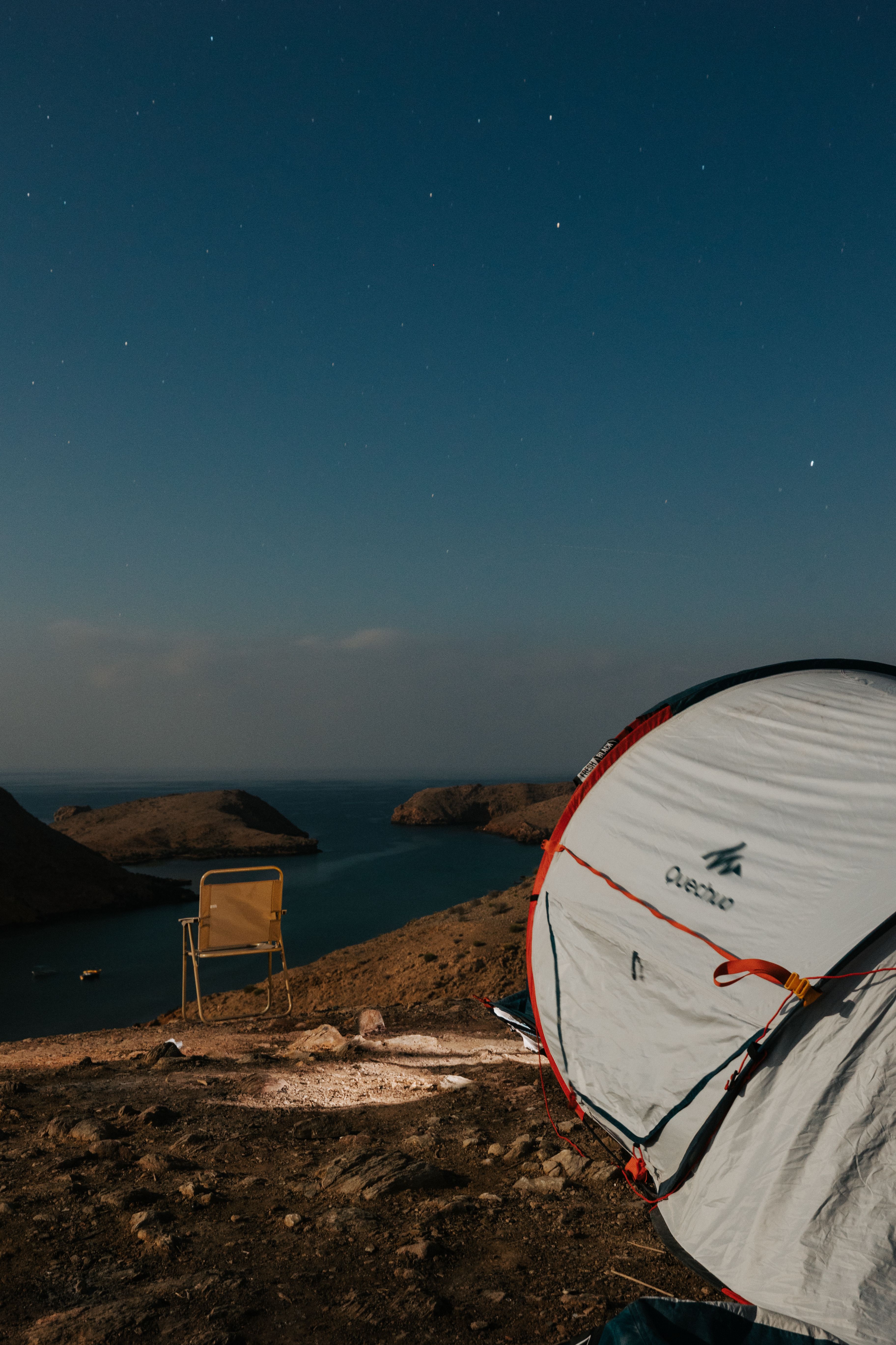 Serene camping scene under the night sky on Muscat's rocky coastline.