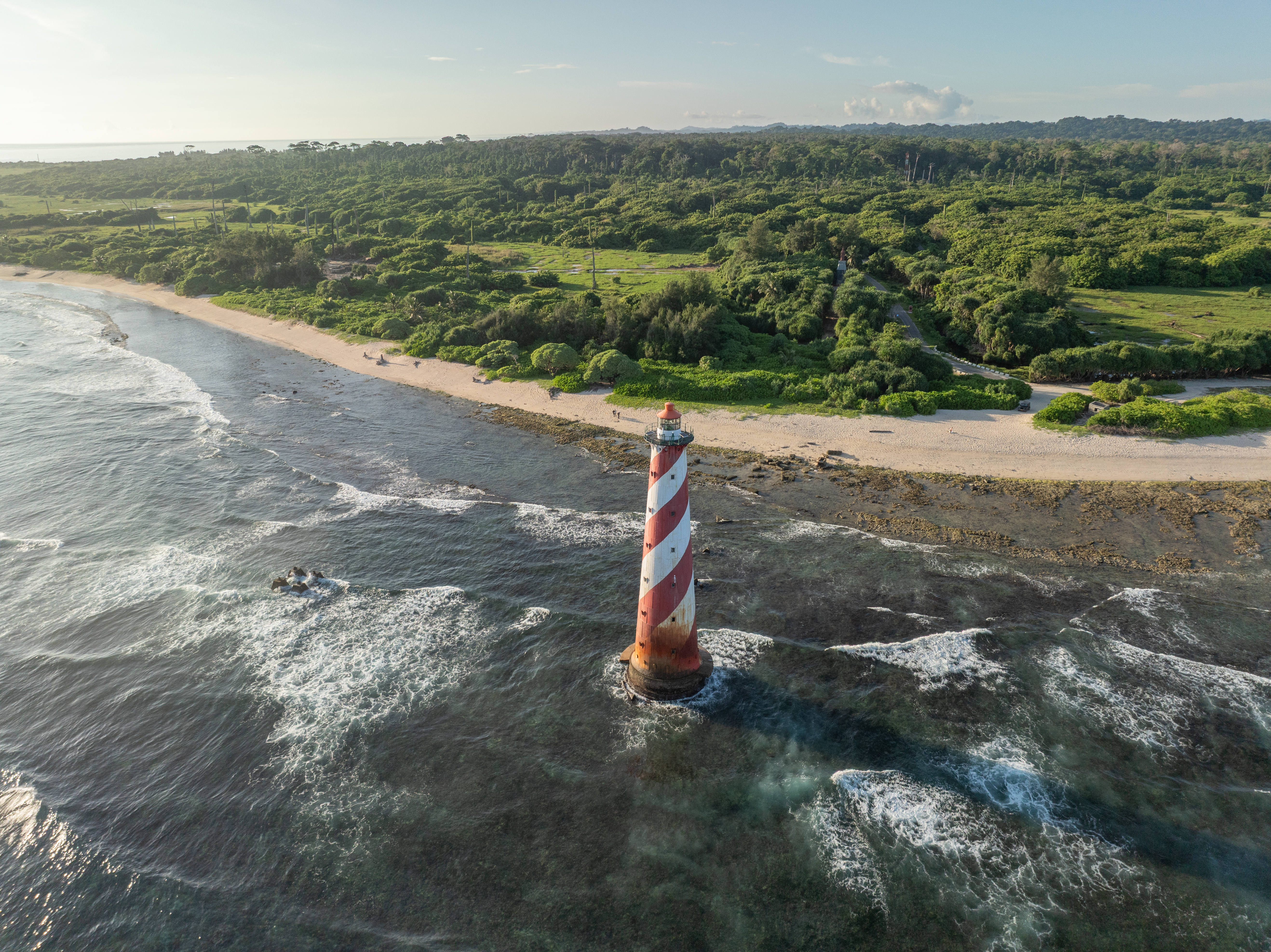 Aerial photograph of Indira Point Lighthouse, Great Nicobar Island, India, surrounded by lush greenery and ocean waves.. Photo by Nabil Naidu on Pexels