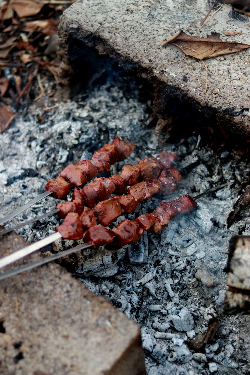 Grilled anticuchos beef heart skewers with aji panca marinade cooking over charcoal flames