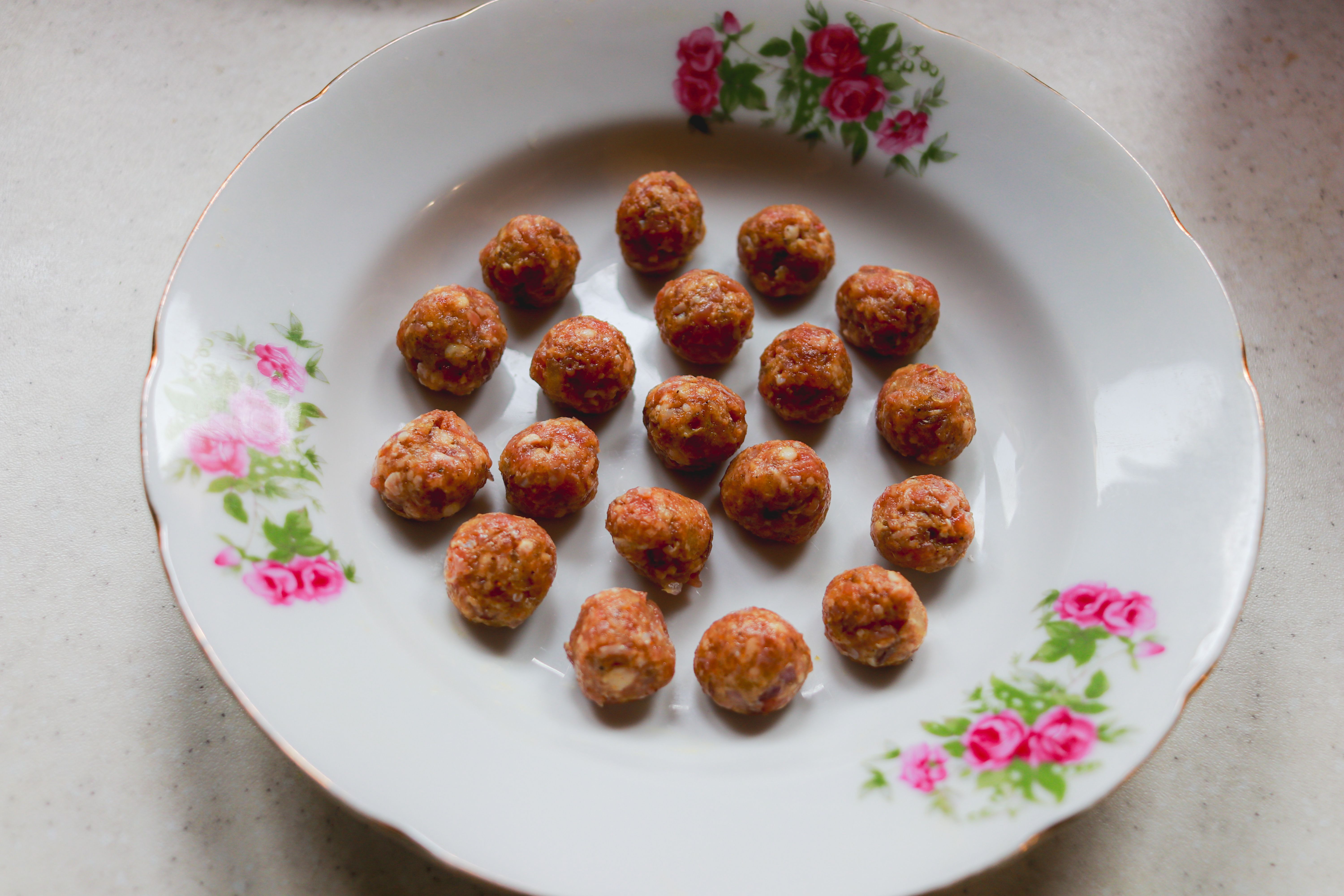 Appetizing homemade meatballs arranged on a vintage floral plate.
