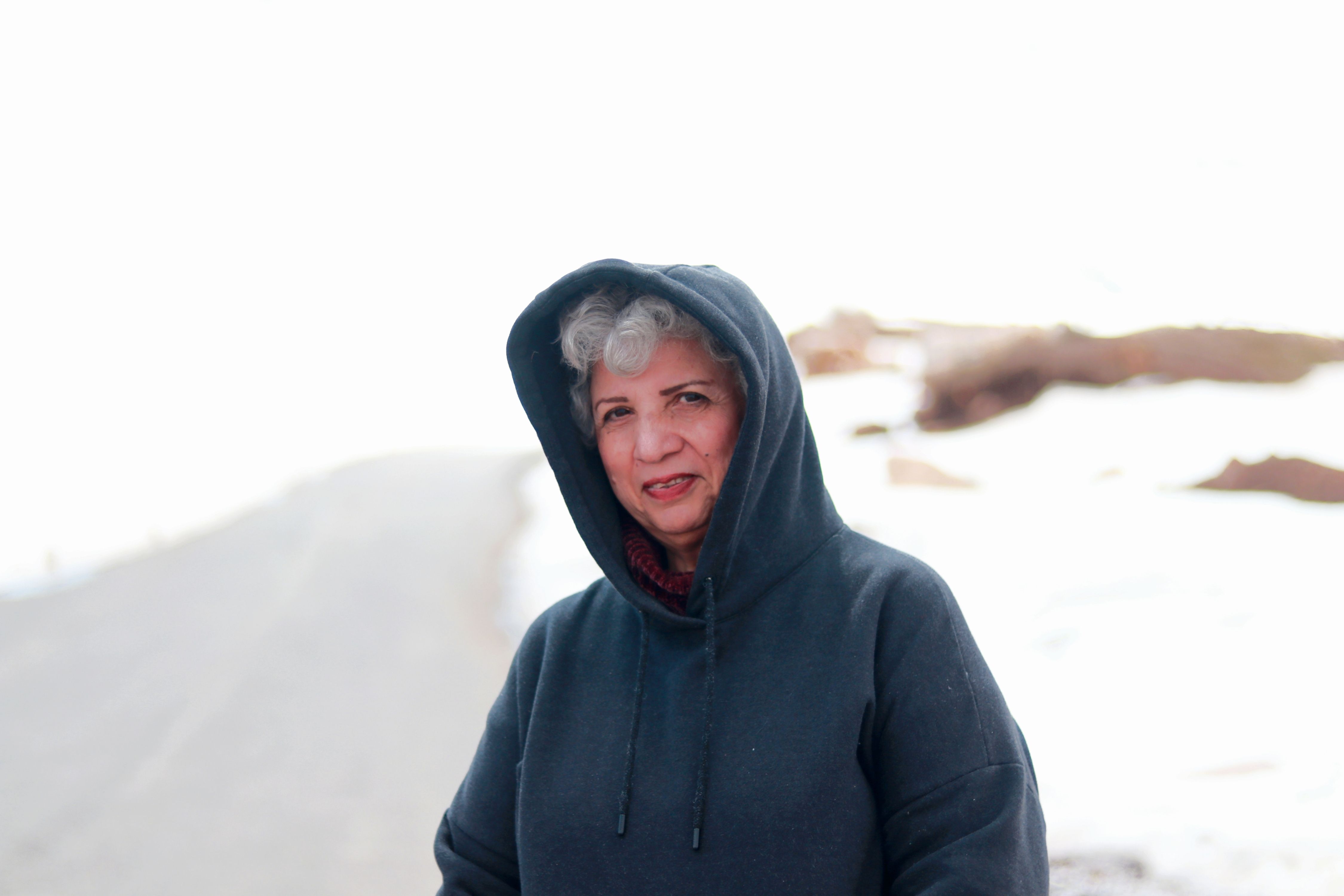 Portrait of a senior woman wearing a hoodie in a snowy outdoor setting.