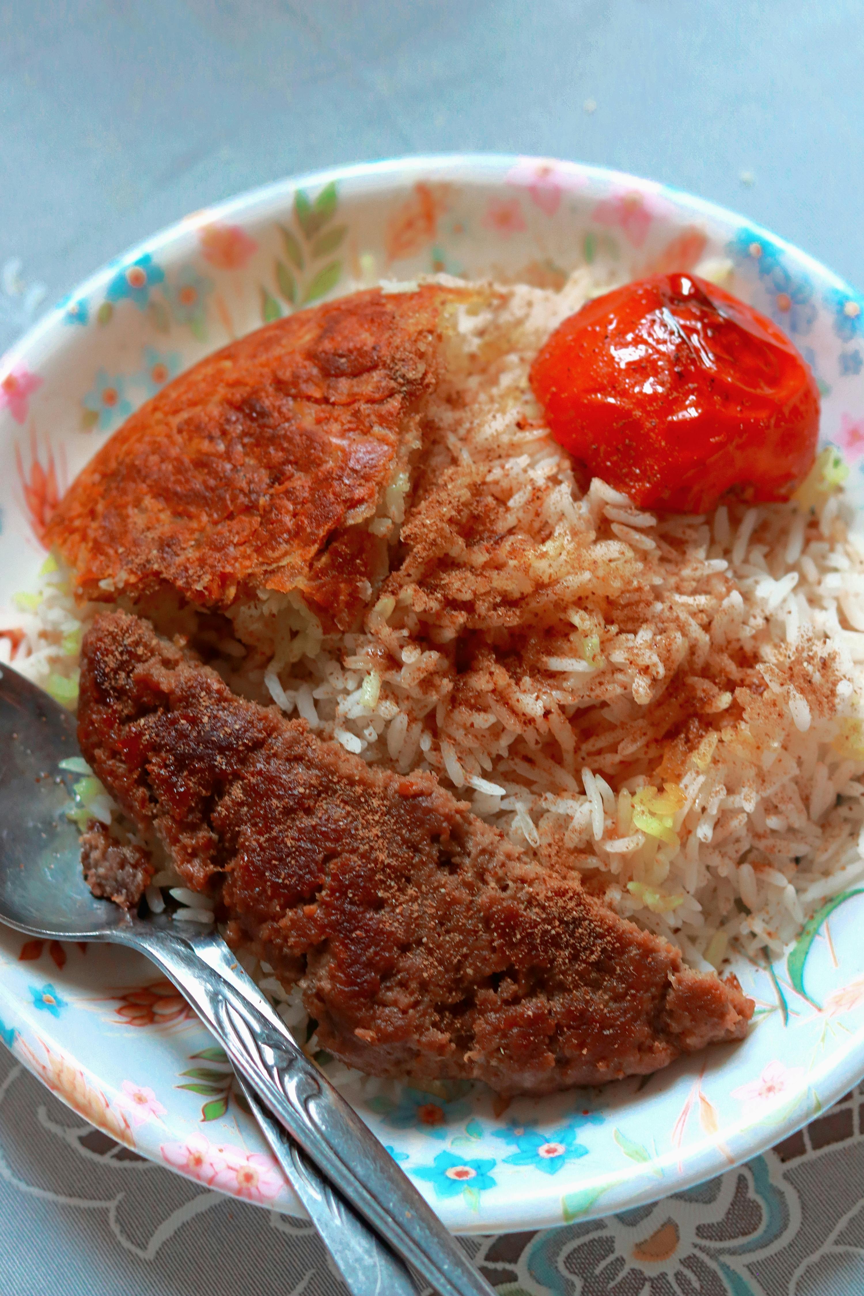 A delicious plate of rice topped with kebabs and roasted vegetables, showcasing Middle Eastern cuisine.