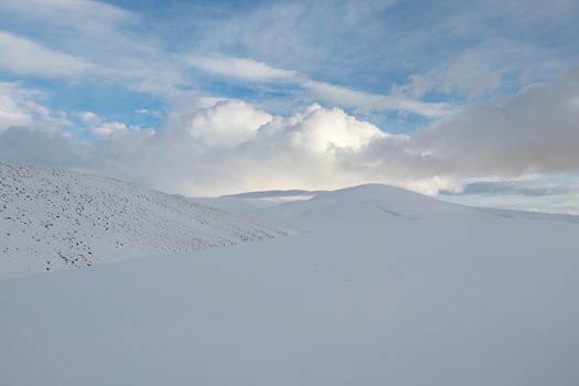 Serene snowy landscape with gentle hills and a vibrant blue sky, perfect for winter themes.