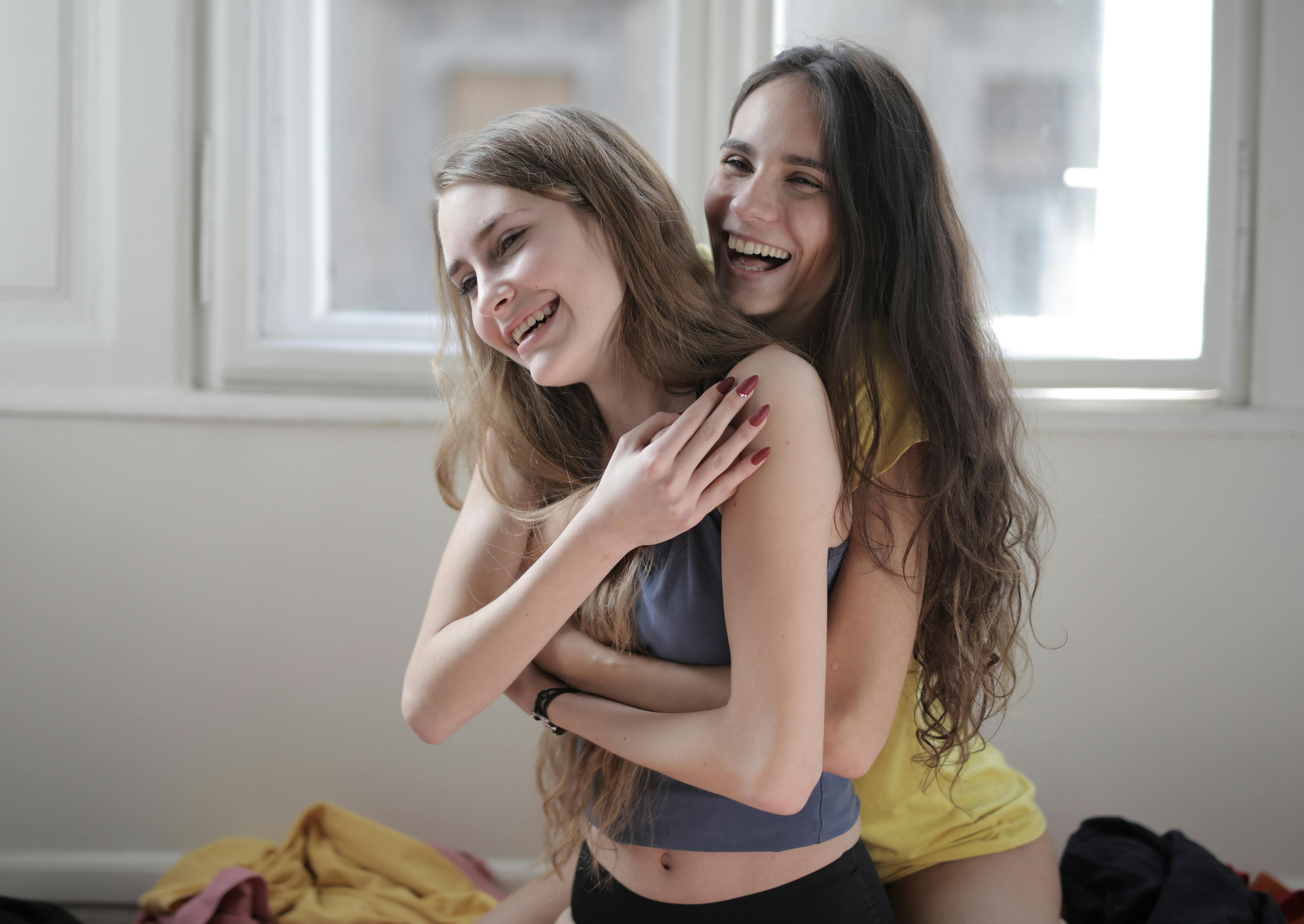 laughing girlfriends hugging in living room