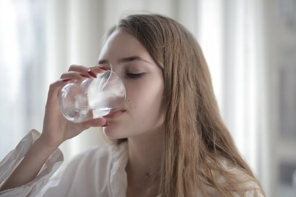 Wanita sedang minum air putih dari gelas untuk meredakan cegukan tiba-tiba