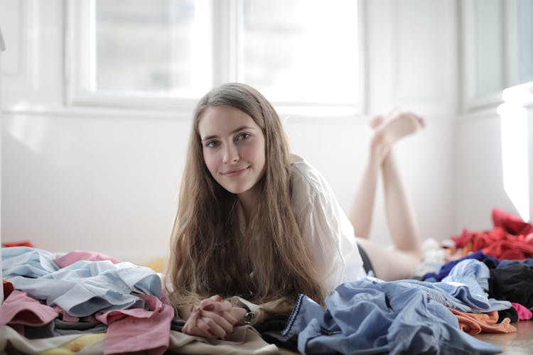 Positive Young Woman In Messy Room With Clothes