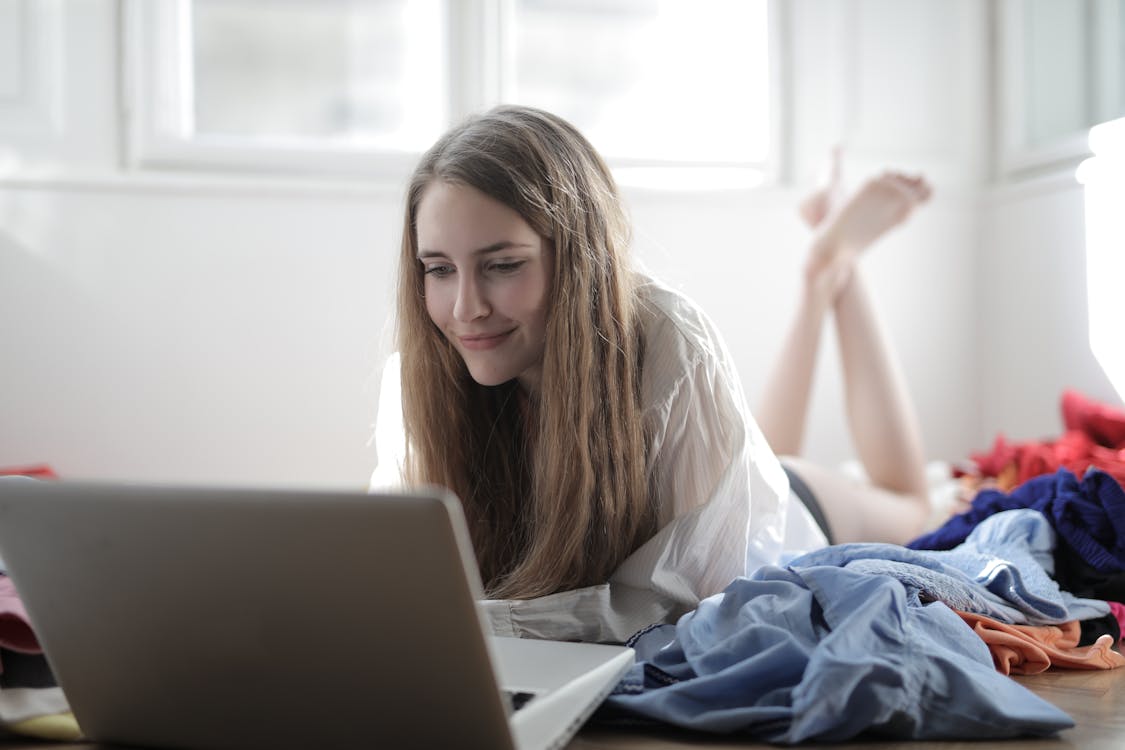 Mujer Joven mira el ordenador portáil, decidiendo si usar vinted o wallapop