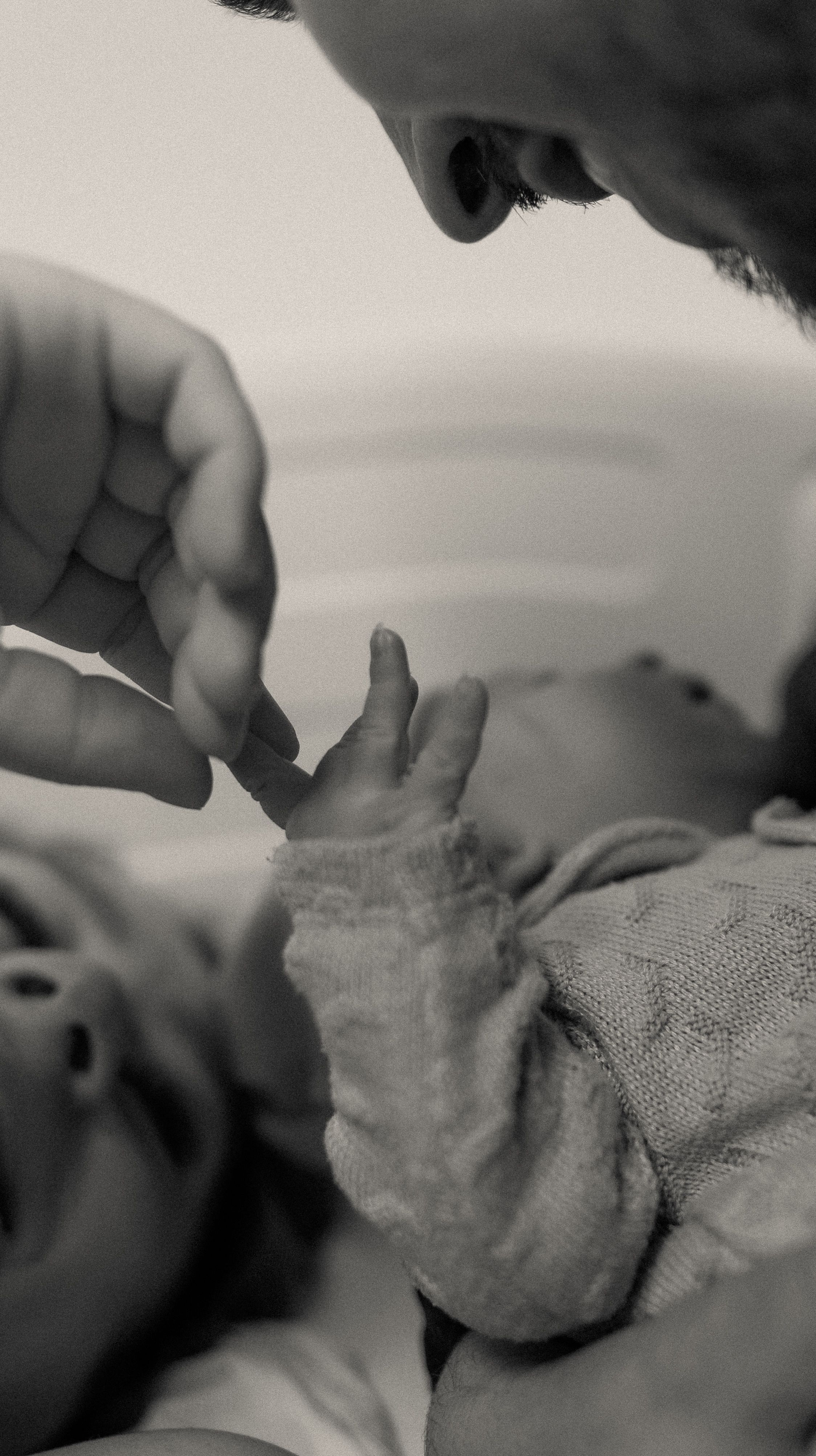 Intimate black and white photo of a parent holding a newborn baby, highlighting tender bonds.