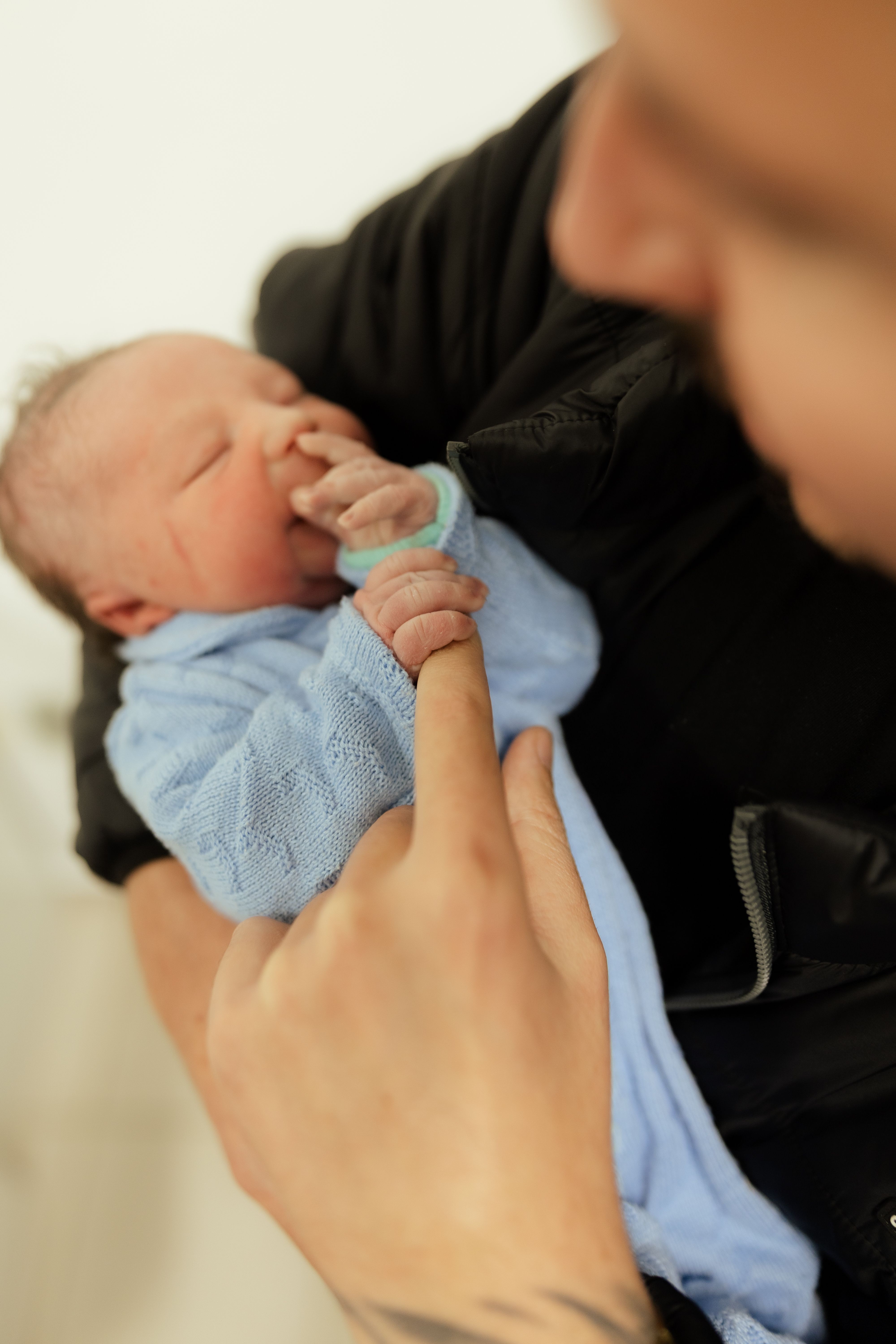 Tender moment of a newborn gently holding a parent's finger. Heartwarming and intimate family scene.