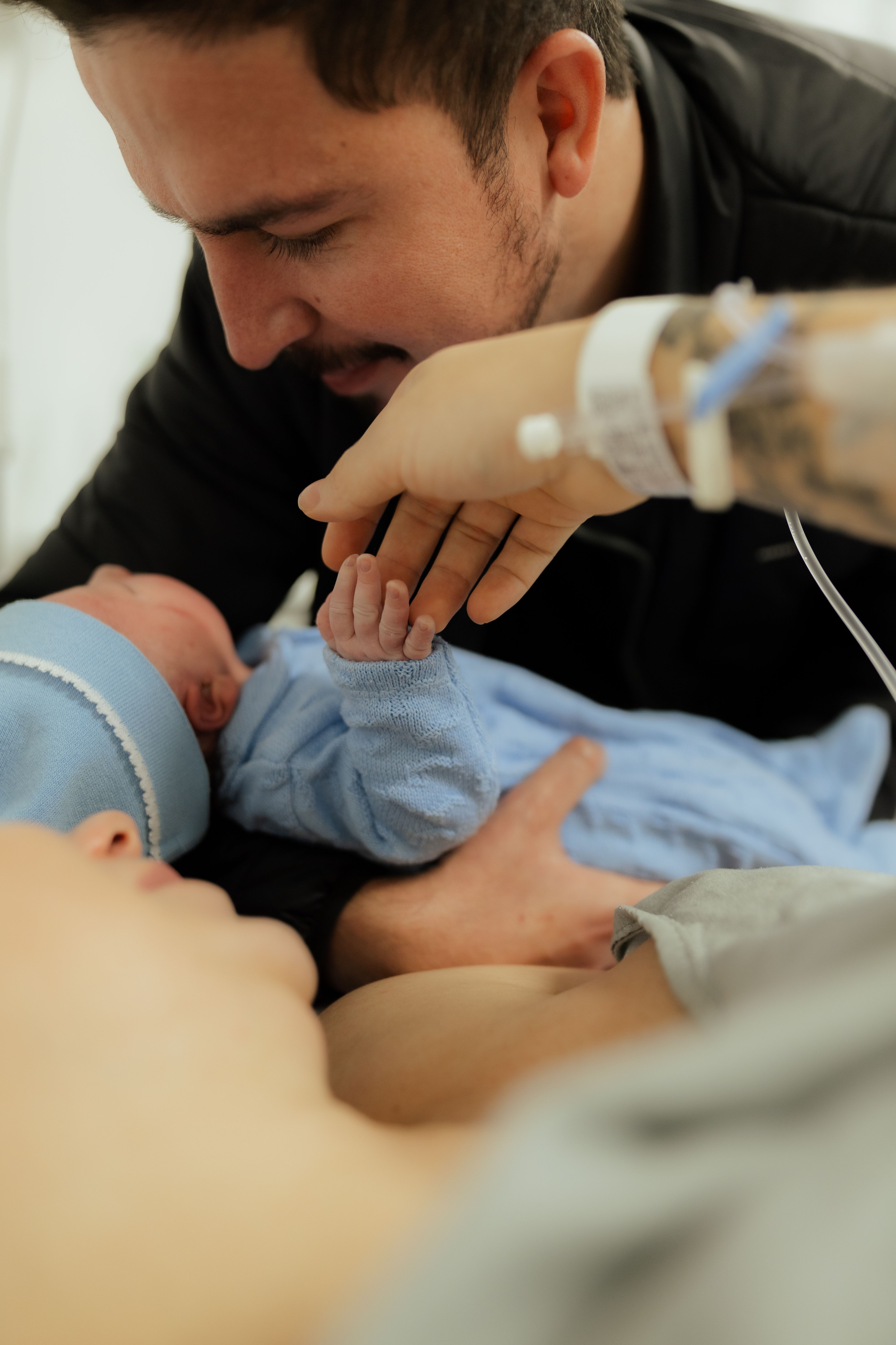 A father meets his newborn baby in a hospital setting, capturing a tender family bond.