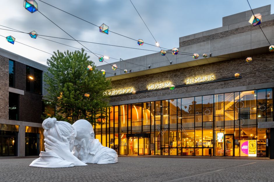 Evening view of Sittard's Ligne Cultural Center with modern sculpture and festive lights.