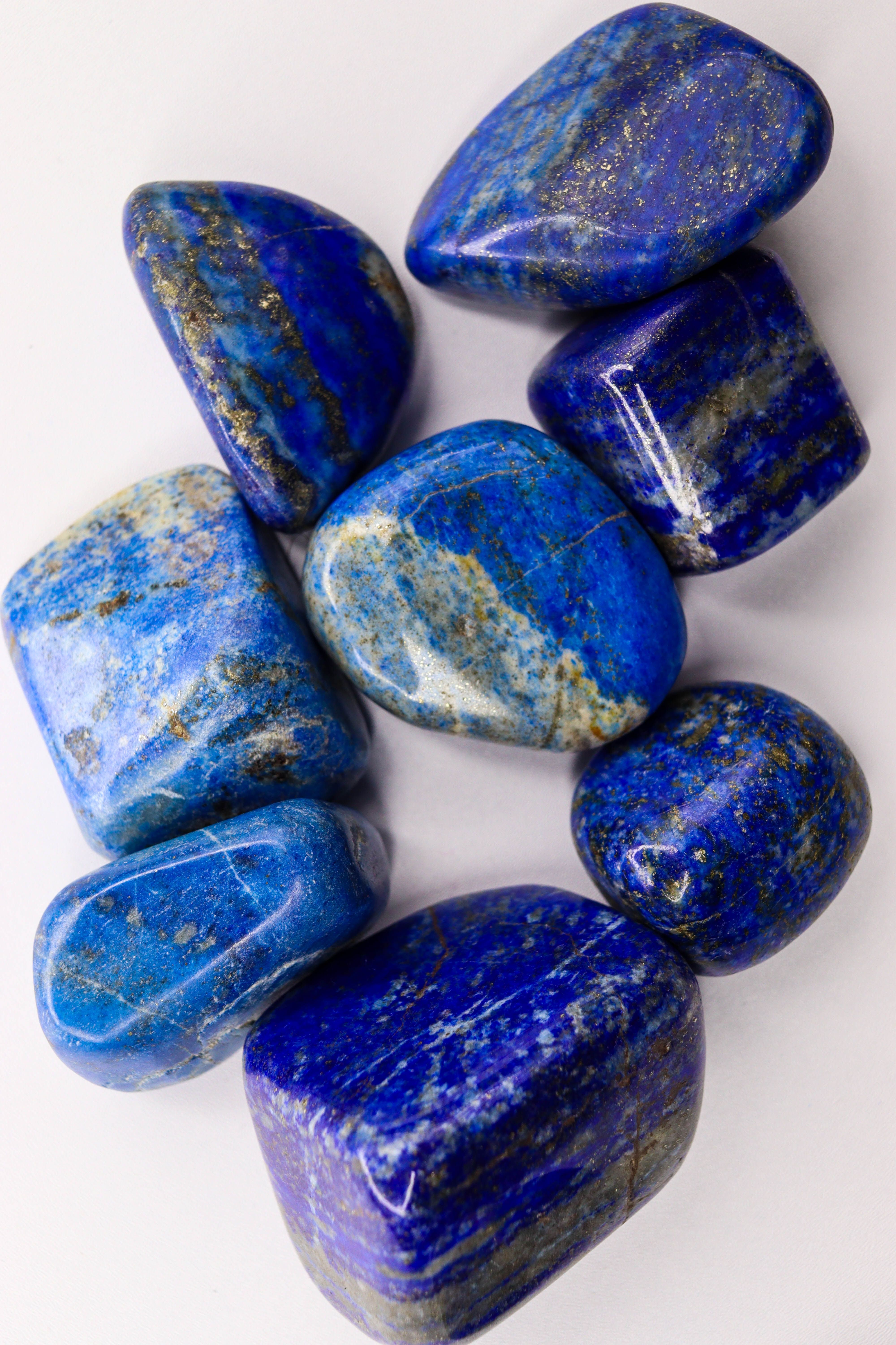 High-angle view of polished blue lapis lazuli stones on a white background.