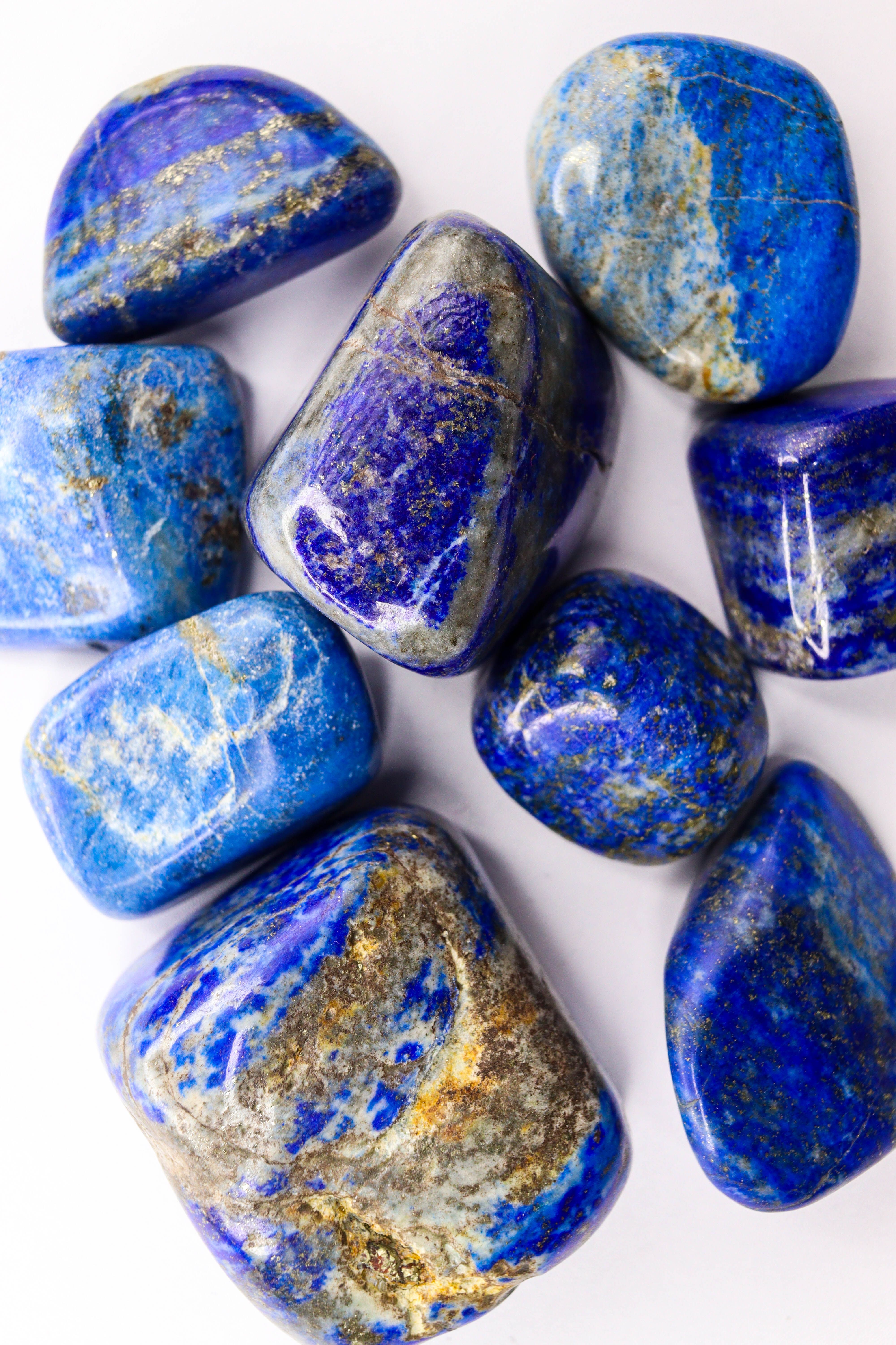 Close-up of vibrant blue and gold lapis lazuli gemstones against a white background.