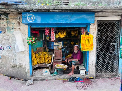 Free Street vendor selling bananas in a vibrant market stall with traditional elements. Stock Photo