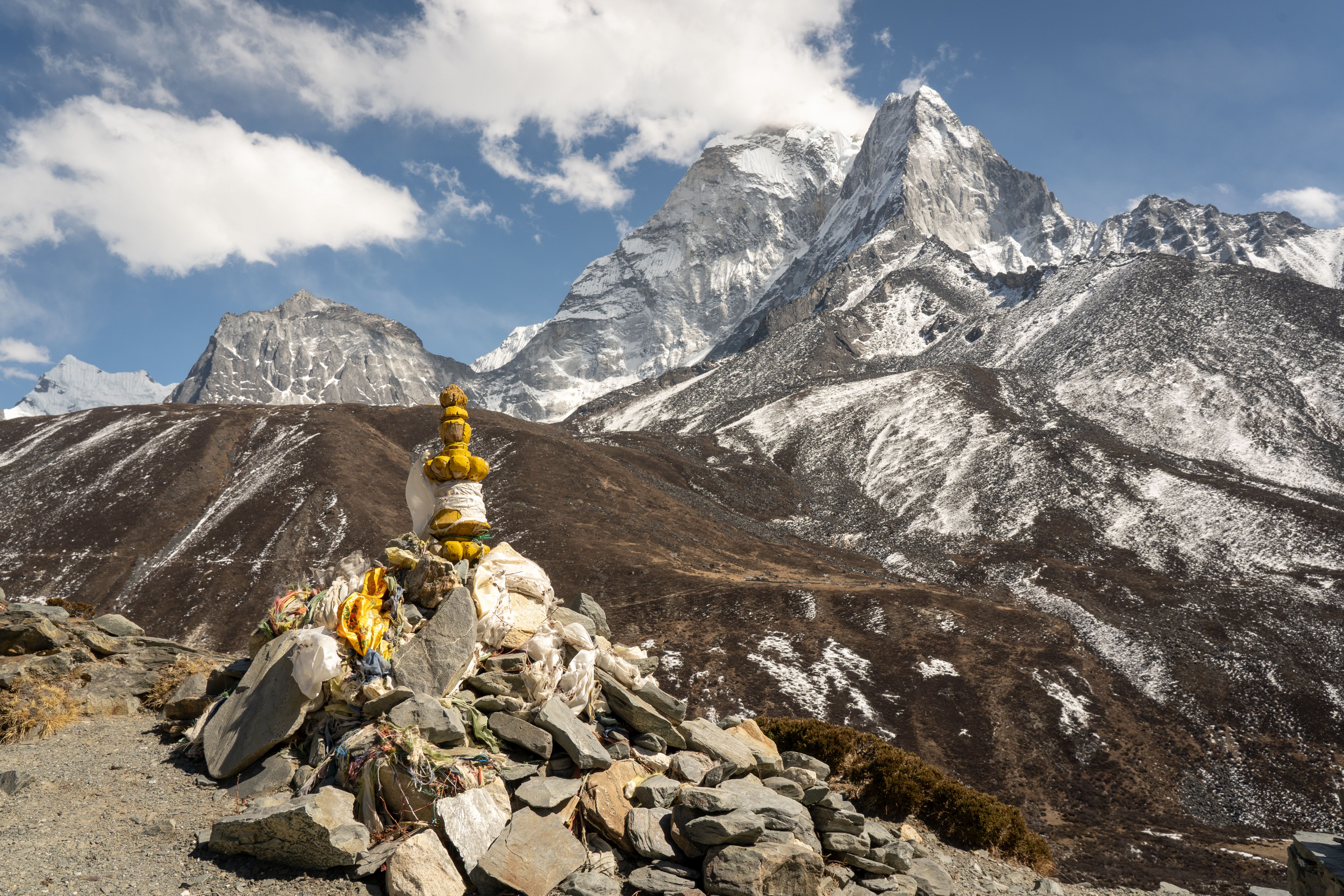 Beautiful view of the Himalayas with a traditional cairn foreground under a clear blue sky.