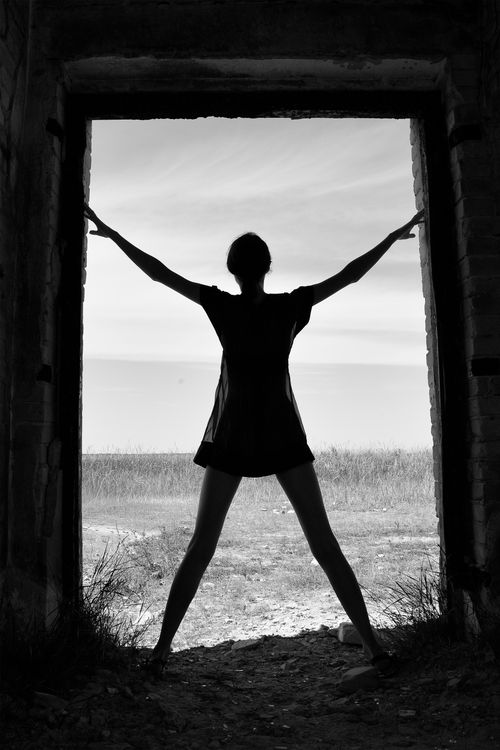 Free A woman stands in silhouette inside a ruined doorway, symbolizing freedom and mystery. Stock Photo