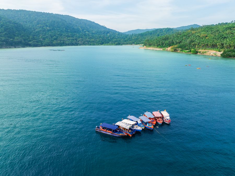 Aerial view of colourful boats on the Andaman Sea near green hills